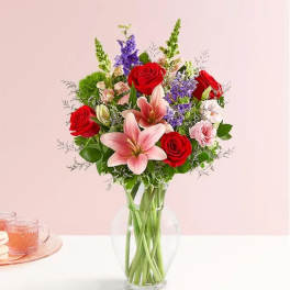Bouquet of red roses and pink lilies in a clear glass vase