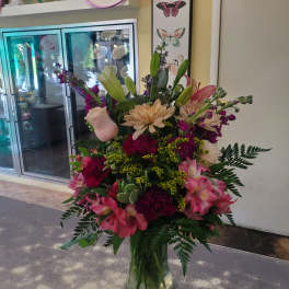 Mixed pink and cream flowers arranged in a clear glass vase