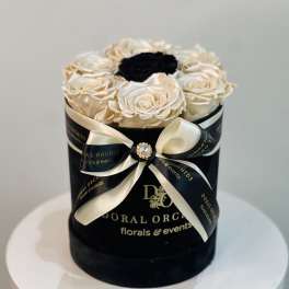 Black hatbox with cream roses and a black center rose, tied with ribbon