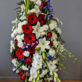 Standing floral spray with red, white, and blue flowers on a ribboned easel