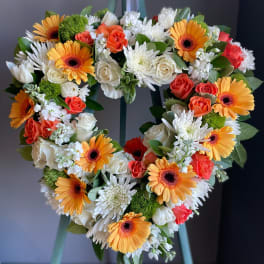 Heart-shaped floral wreath with orange gerbera daisies, white roses, and white mums