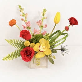 Mixed floral arrangement in a wooden box with red, yellow, and pink blooms