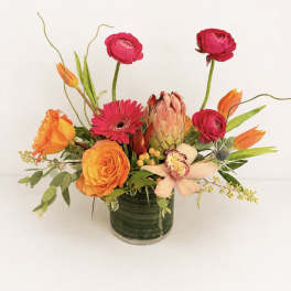 Bright mixed flower arrangement in a green glass vase
