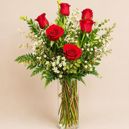 Red roses and white filler flowers in a clear glass vase