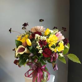Mixed bouquet in a glass vase with yellow, pink, and burgundy flowers