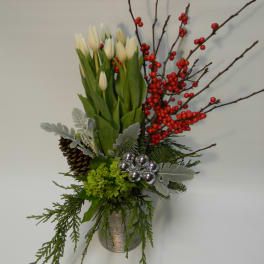 White tulips in a silver vase with red berries and pinecones