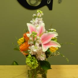 Pink lilies and mixed flowers in a clear glass vase