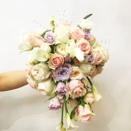 Handheld bouquet of pastel roses and calla lilies