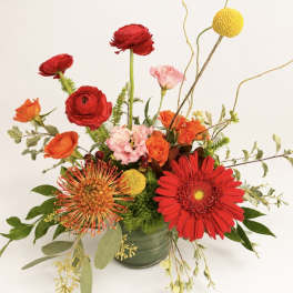 Bright mixed bouquet in a glass vase with red, orange, pink, and yellow blooms