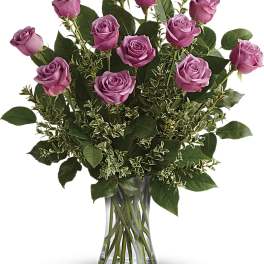 Pink roses arranged in a clear glass vase with mixed greenery