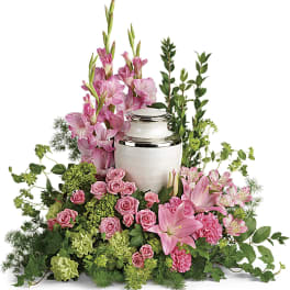 Pink flowers arranged around a white urn with greenery