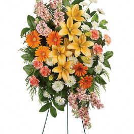 Standing floral spray with yellow lilies, orange daisies, and pink blooms