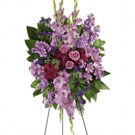 Standing floral spray with purple flowers and pink roses on a wire easel