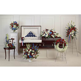 Casket spray and standing floral tributes in red, white, and blue