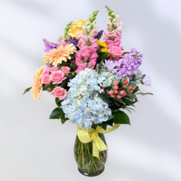 Colorful mixed bouquet in a glass vase with a yellow ribbon