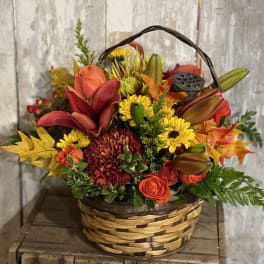 Autumn flower basket with orange roses and yellow mums in a woven basket