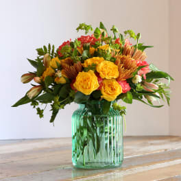 Yellow and red mixed bouquet in a green glass vase