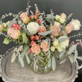 Mixed roses in a clear glass vase with airy eucalyptus on a silver tray