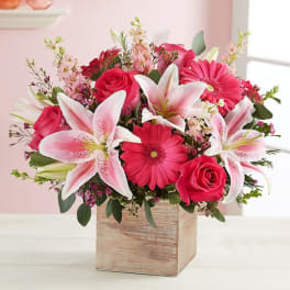 Pink lilies, roses, and gerbera daisies in a wooden cube vase