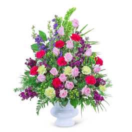 Mixed bouquet of pink roses, carnations, and purple flowers in a white vase