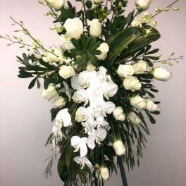 Tall white floral spray with roses and orchids on an easel