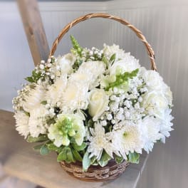 White floral basket arrangement with roses, chrysanthemums, and baby's breath