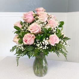 Pink roses arranged in a clear glass vase with white filler flowers