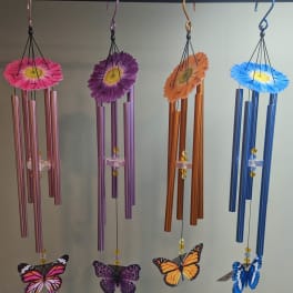 Four hanging wind chimes with daisy tops and butterfly ornaments.