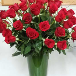 Red roses arranged in a tall glass vase
