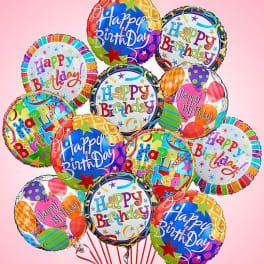 Cluster of colorful Happy Birthday balloons on a pink background