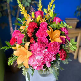 Bright pink and orange floral arrangement in a white vase