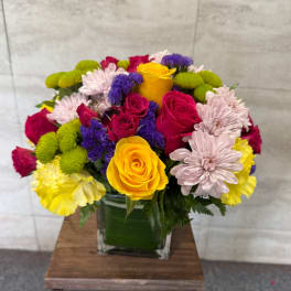 Colorful bouquet of roses and chrysanthemums in a square glass vase
