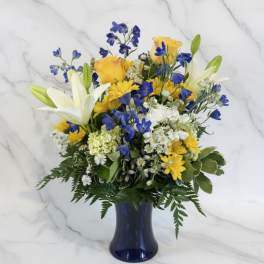 Blue and yellow mixed bouquet in a dark vase