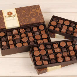 Boxes of assorted chocolates on a light wood surface
