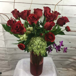 Red roses in a tall vase with purple orchids