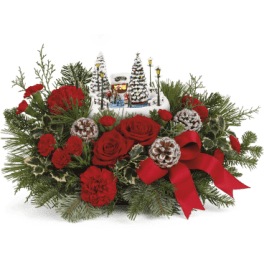 Red roses and carnations with a Christmas village centerpiece