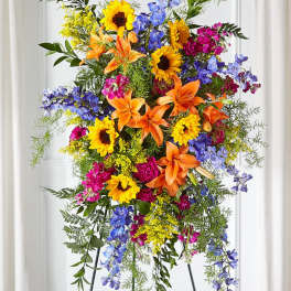 Tall standing floral spray with sunflowers, lilies, and blue flowers
