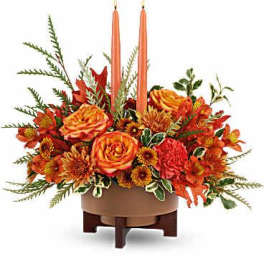 Orange floral centerpiece with two tall candles in a low bowl
