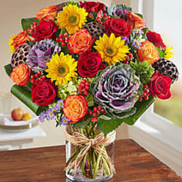 Colorful bouquet of roses and sunflowers in a clear glass vase