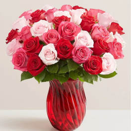 Bouquet of red, pink, and white roses in a red glass vase