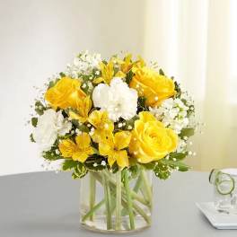 Yellow and white flower bouquet in a clear glass vase