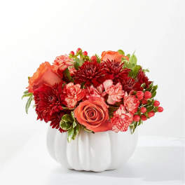 Orange roses and red chrysanthemums in a white pumpkin vase
