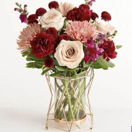 Mixed bouquet of roses, carnations, and chrysanthemums in a glass vase