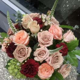 Bouquet of blush and peach roses with burgundy carnations