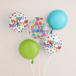 Cluster of colorful birthday balloons with polka dots and "Happy Birthday" text