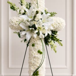 White floral standing cross with lilies and roses on an easel