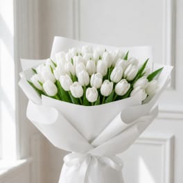 Bouquet of white tulips wrapped in white paper with a ribbon