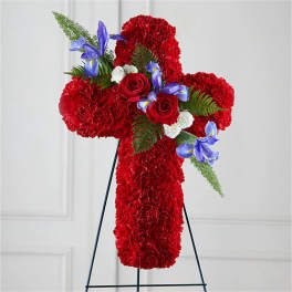 Red floral cross arrangement with roses and purple irises on a stand