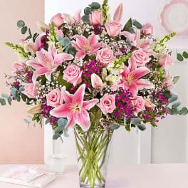 Pink lilies and roses arranged in a clear glass vase