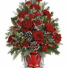 Red roses and carnations in a glass vase with pinecones and evergreen accents